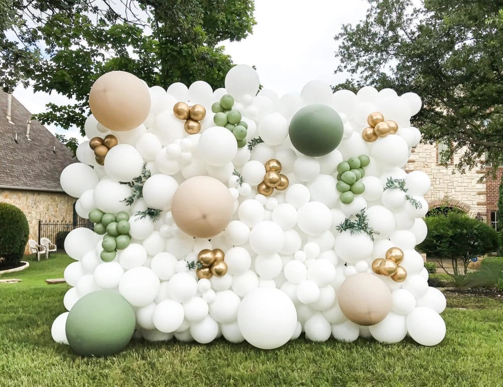 a bunch of balloons that are on the grass in front of a house with a house in the background