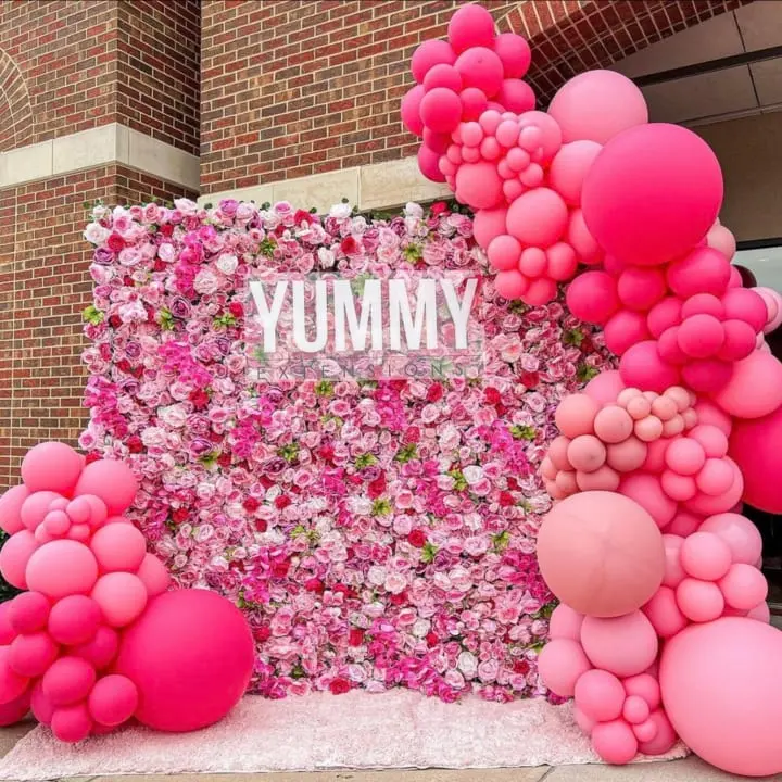 a large display of pink and pink balloons with the word yummy written on the top of it in front of a brick building