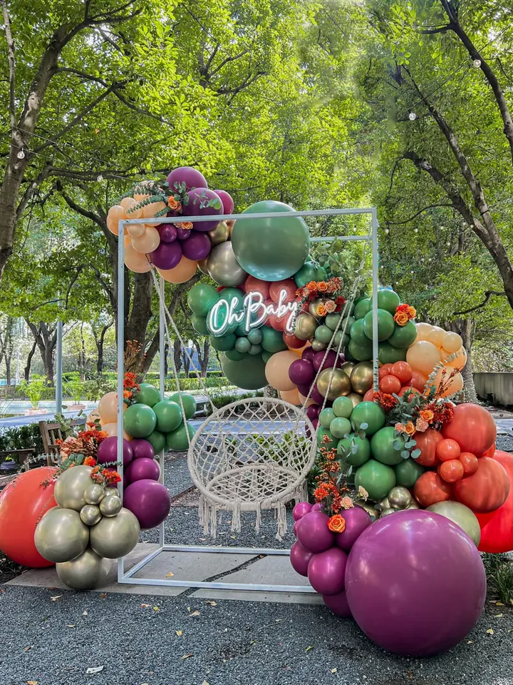 A vibrant display of various fresh fruits and vegetables, including tomatoes, eggplants, and other produce, arranged in an artistic manner against a backdrop of lush, green foliage.