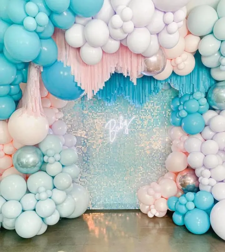 a bunch of balloons and streamers on a table with a backdrop of blue and white balloons and streamers
