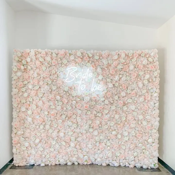 a white wall with pink flowers and a white sign that says bride to be on the side of it