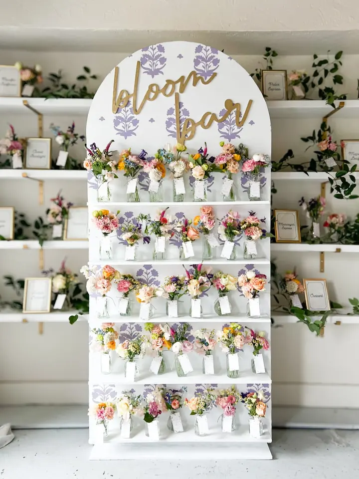 A floral display with various colorful flowers arranged in small vases on a white shelving unit, with the text "Labor Day" prominently displayed at the top.