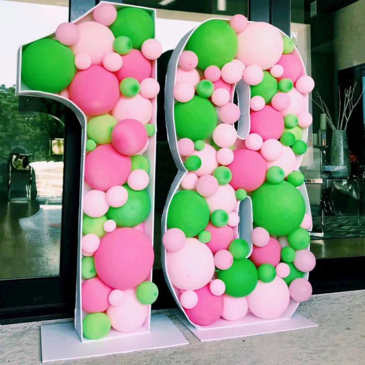 a large number made out of balloons sitting in front of a store front door with a large number on the outside of it