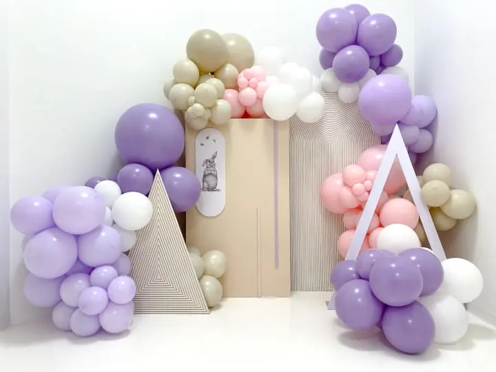 a bunch of balloons that are in a room with a door and a clock on the wall behind them