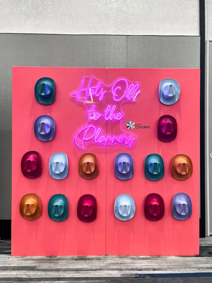 A vibrant red wall displays a neon sign that reads "It's all to the planets", surrounded by an array of colorful, spherical objects.