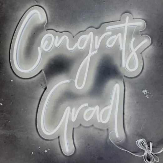 a neon sign that says congrats and grad on a gray background