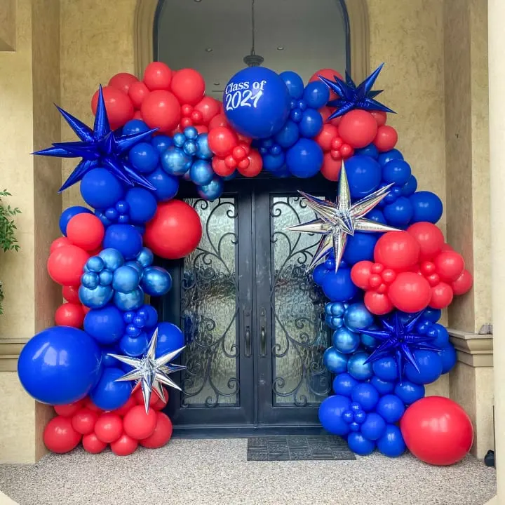 a blue, red and white wreath with stars and balloons on the front door of a house that is decorated for the fourth of july