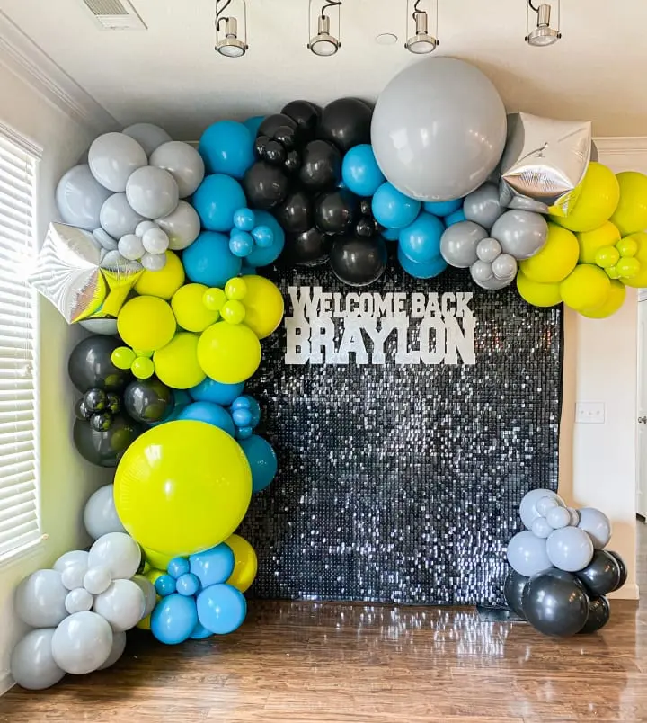 a room filled with balloons and a sign that says welcome back brayton on the front of the room