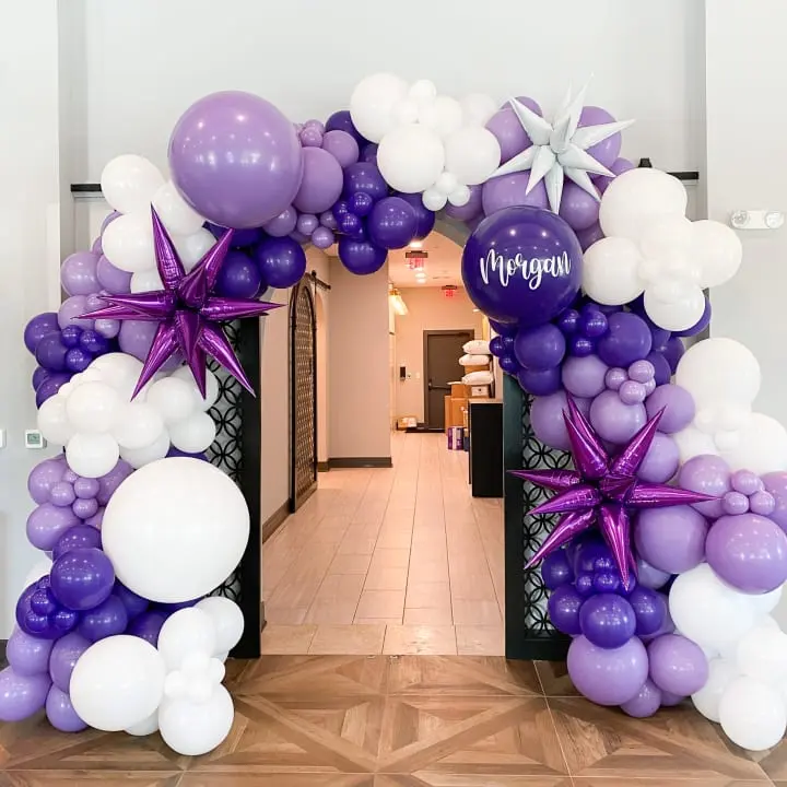 a purple and white balloon arch decorated with stars and balloons for a birthday or baby's first birthday