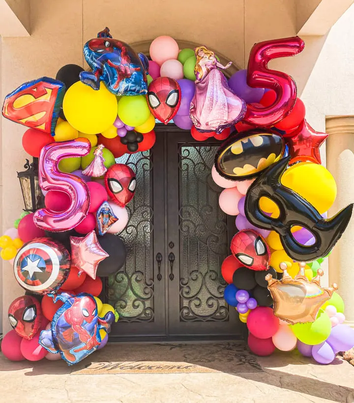 a bunch of balloons that are on the front of a door that is decorated with a shield and masks