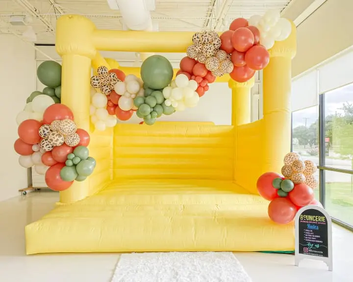 a large yellow inflatable chair with a bunch of balloons on top of it in a room with a white rug on the floor