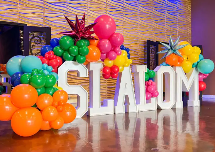 a sign that says slam with balloons and a star on top of it in front of a wall of balloons