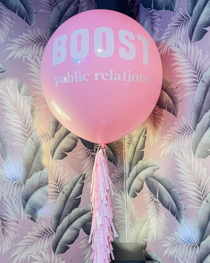 a pink balloon with a tassel hanging from it's side in front of a floral wallpaper