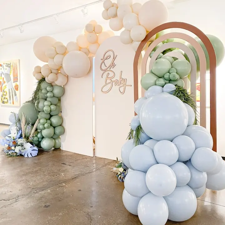 a bunch of balloons that are in the air in a room with a sign on the wall and a bunch of balloons in the air