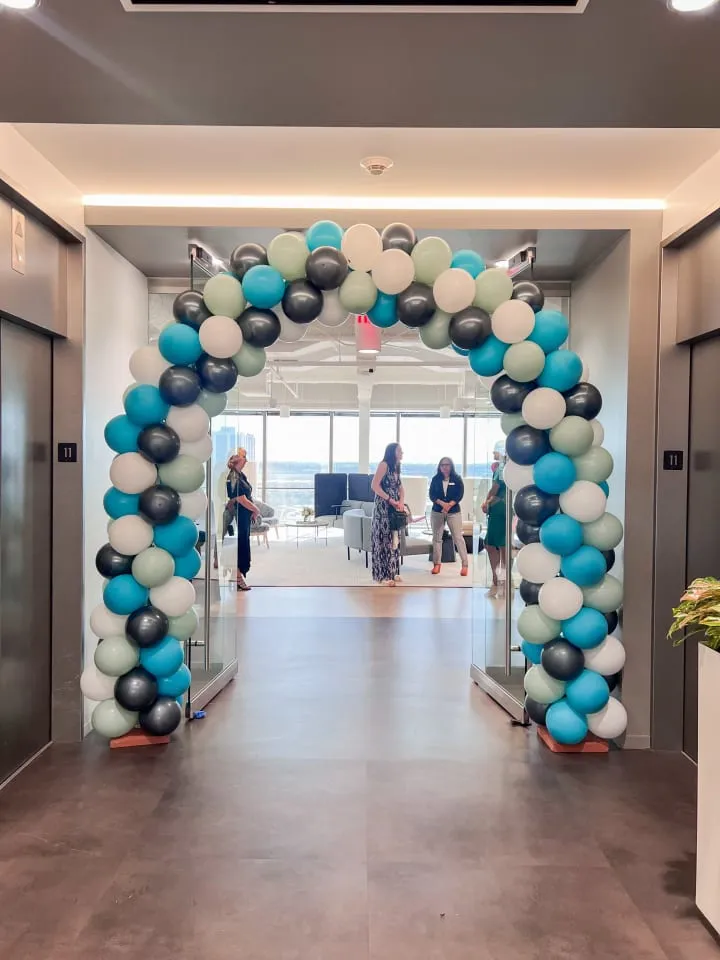 a group of people walking down a hallway with balloons in the shape of a circle on the wall and on the floor