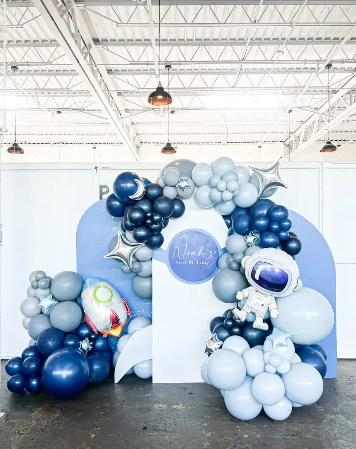 a large balloon arch with a spaceman on it in a large room with white walls and ceilinging