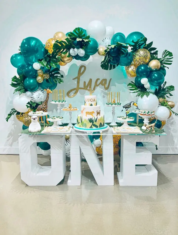 a table with a cake and balloons on it and a one sign in the middle of the table with a cake and balloons in the middle of the table