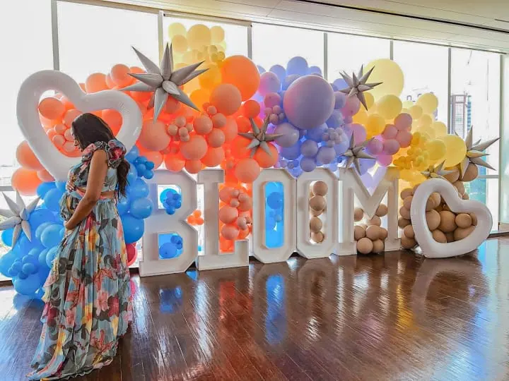 a woman standing in front of a giant balloon wall with the words 2012 and balloons in the shape of stars