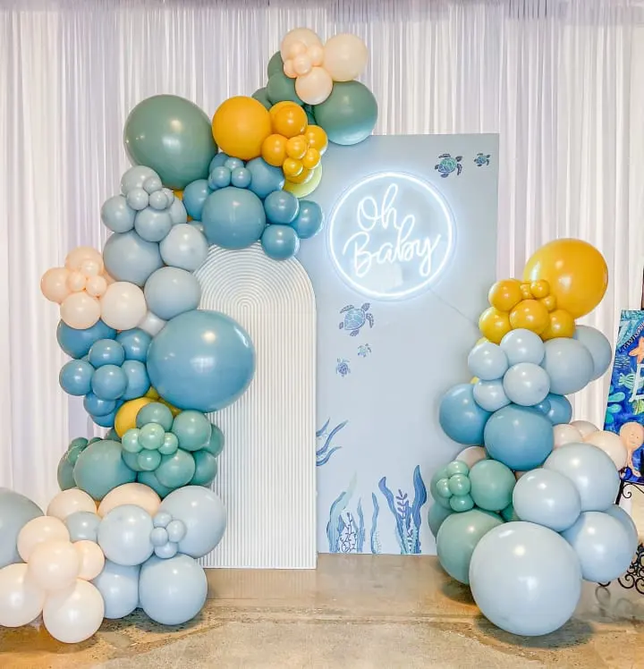 a bunch of balloons that are on a table in front of a sign that says oh baby on it