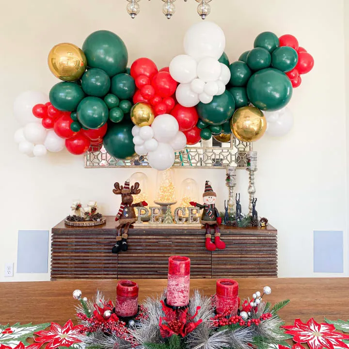 a table with a bunch of balloons on top of it and a christmas centerpiece on top of it