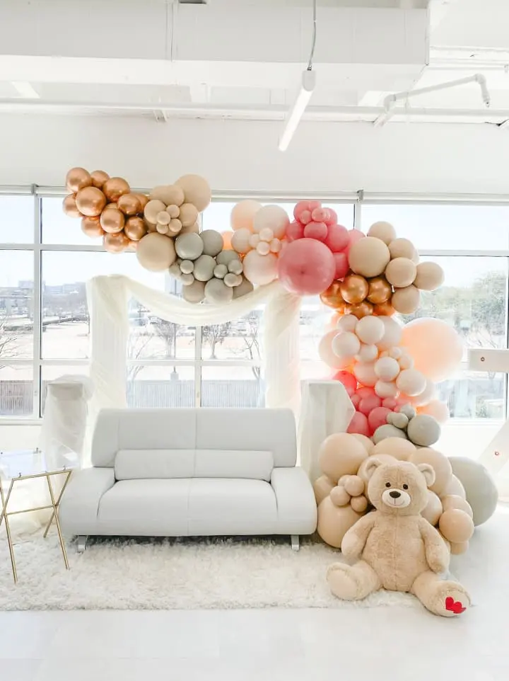 a living room with a couch and a bunch of balloons on the wall and a teddy bear on the floor