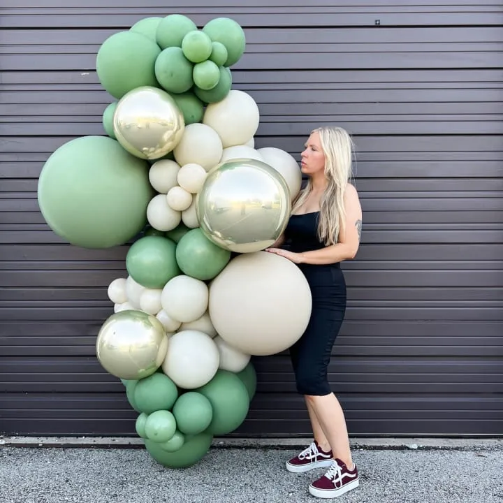 a woman holding a bunch of balloons in front of a wall with a large number of balloons on it