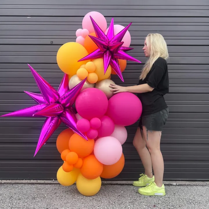 a woman standing with a 6 ft balloons garland and starbursts