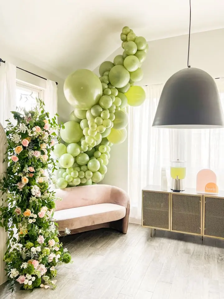 a living room filled with furniture and a bunch of green balloons hanging from the ceiling over the couches