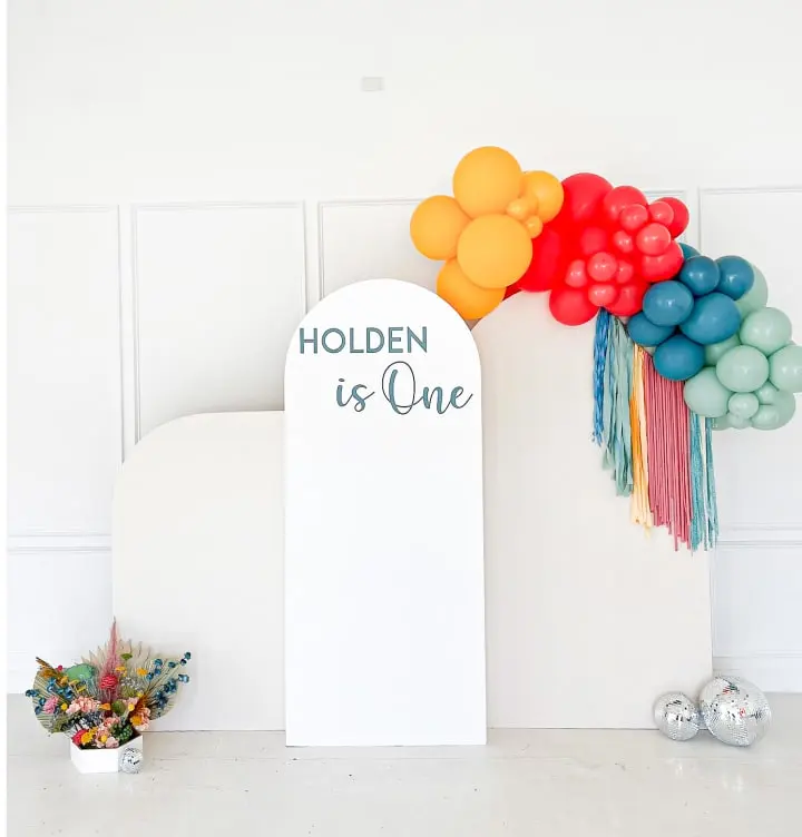 a balloon arch with a sign that says, holiday is one and a bunch of balloons in the background