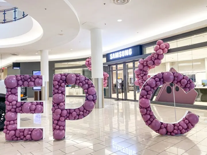 a large number of balloons in the shape of a pig and a piggy bank sign in a mall