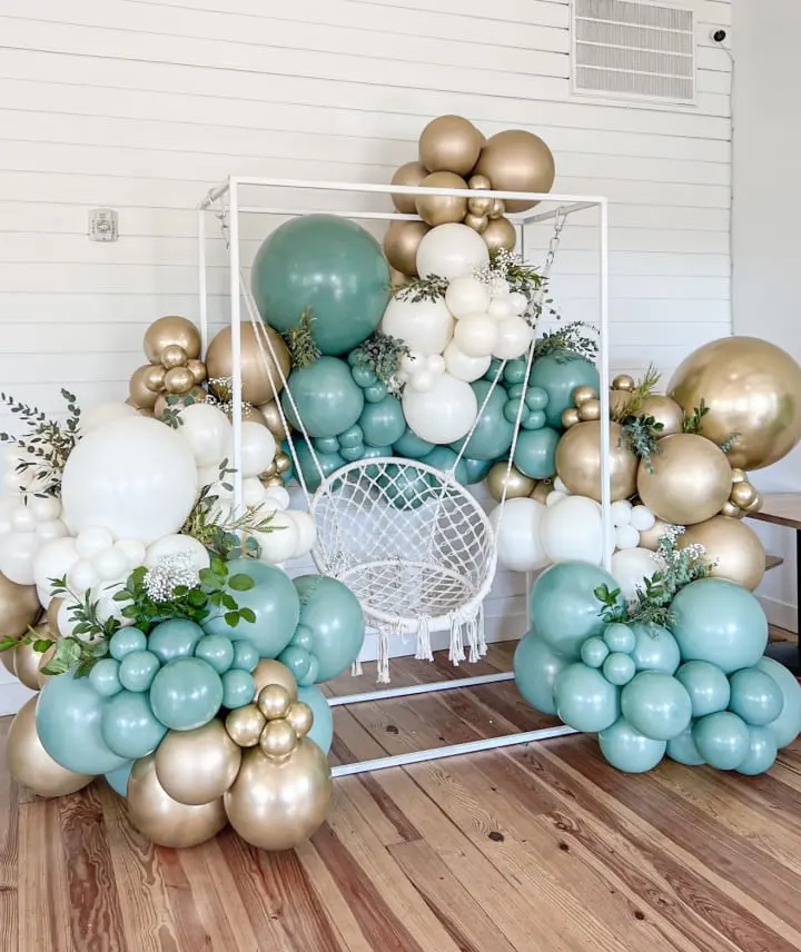 a bunch of balloons that are on top of a wooden table with a white chair in front of it