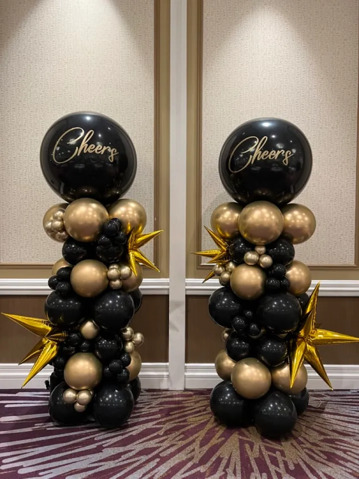 a couple of black and gold balloons sitting on top of each other in front of a wall with gold stars