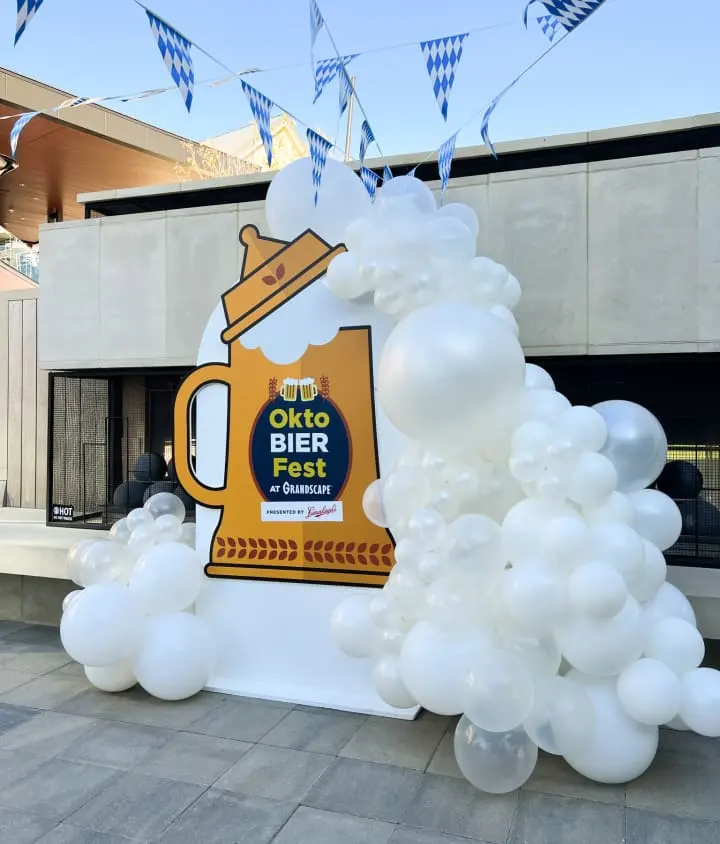 a giant beer sign with balloons in the shape of a rocket and a beer mug on top of it