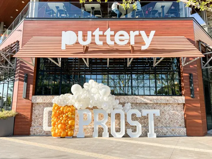 a sign that says buttery next to a building with a bunch of balloons in front of it and a sign that says frosted with the word frosted buttery
