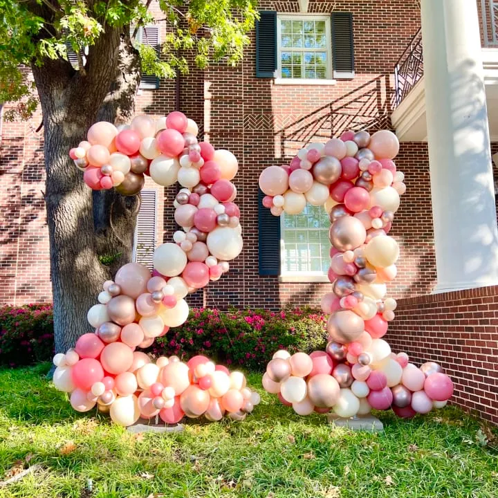 a large number made out of balloons in front of a brick building with a tree in front of it