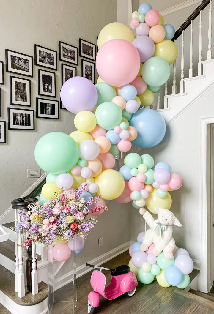 a bunch of balloons that are on the ground near a stair case and a scooter with a bunch of balloons on it