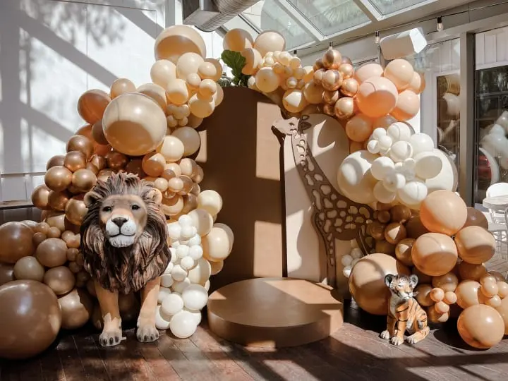 a lion and giraffe made out of balloons in a room filled with other balloons and a giraffe statue