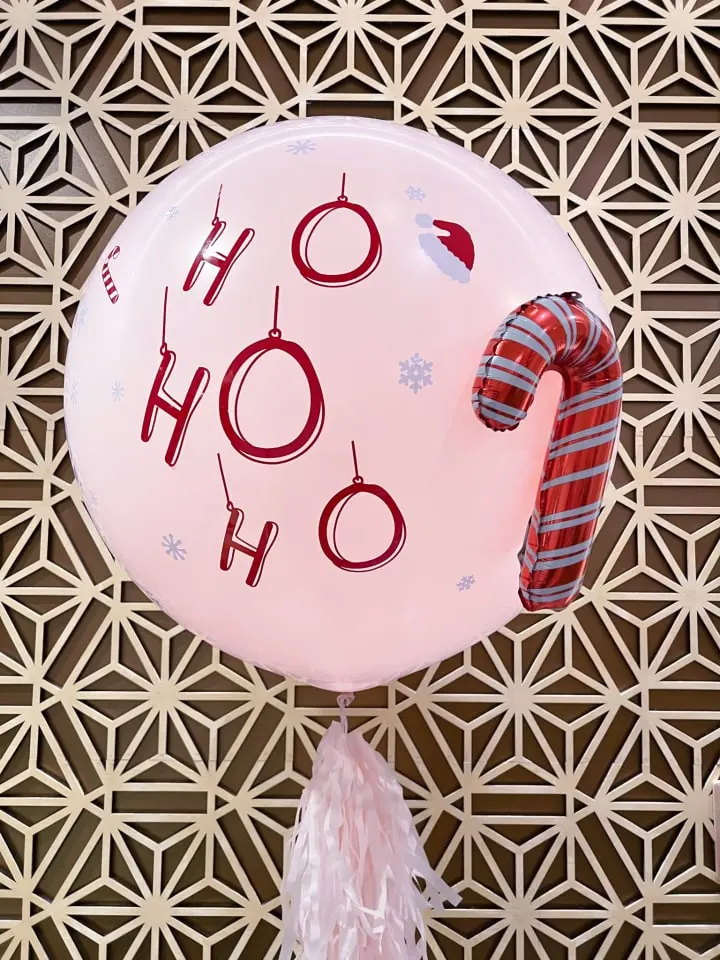 a pink balloon with the words oh oh oh on it hanging from a string on a wall with snowflakes