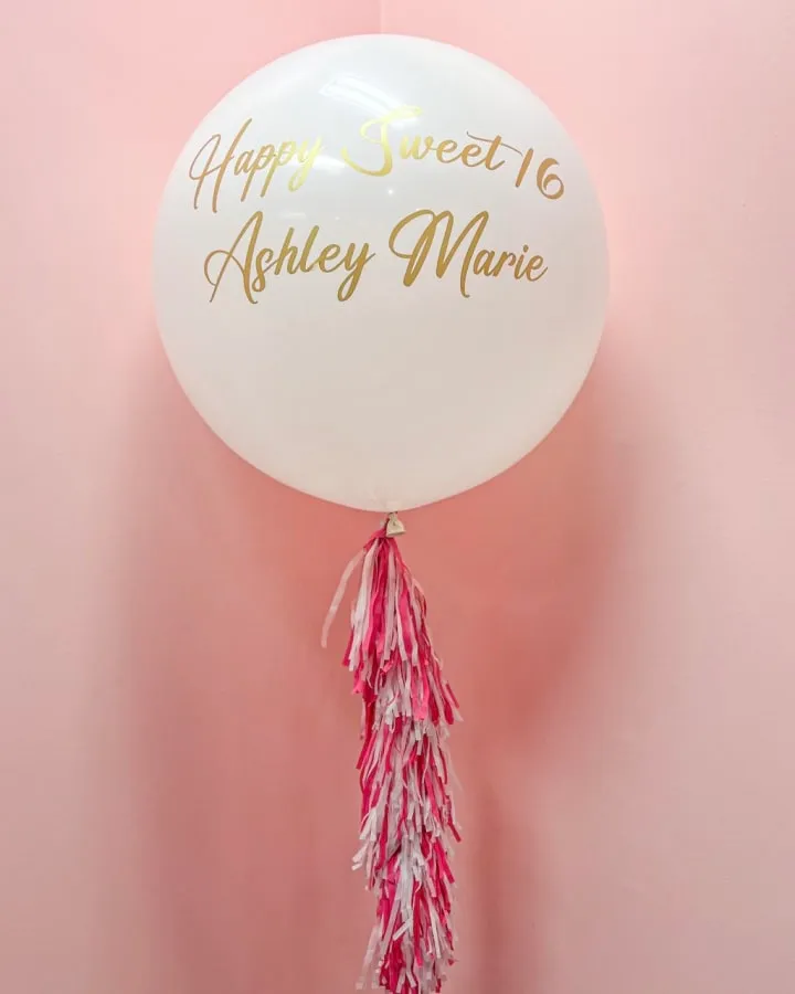 a white balloon with a pink tassel hanging from it's side with a happy sweet 16 written on it
