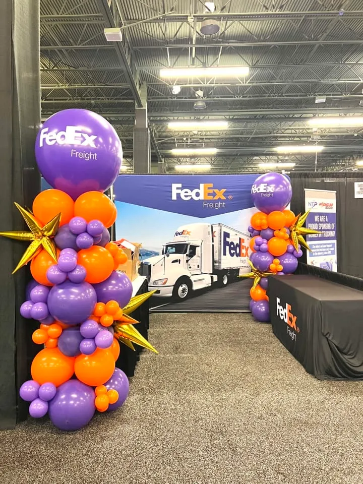 a truck is parked in a warehouse with balloons on the floor and a sign that says fed ex on the side of the truck
