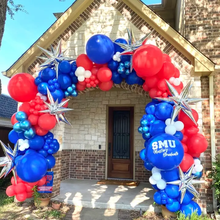a red, white and blue balloon arch in front of a house with a flag and stars on it