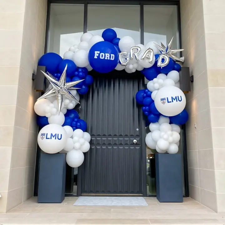 a blue and white balloon arch with a star and the word ford on it and some white and blue balloons in front of a building