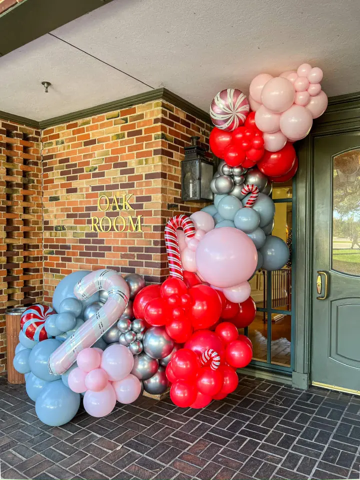 a bunch of balloons that are on the ground outside of a building that has a brick wall and door