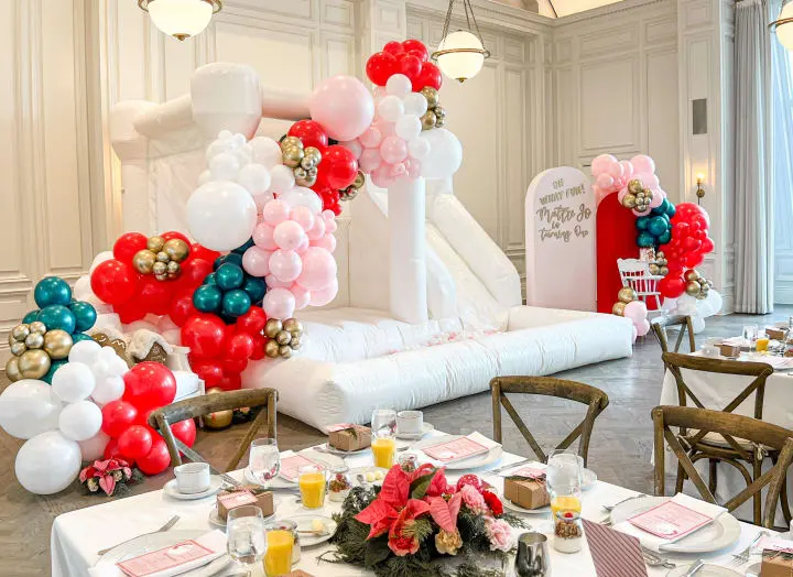 a table set up for a party with balloons and decorations on the table and a slide in the background