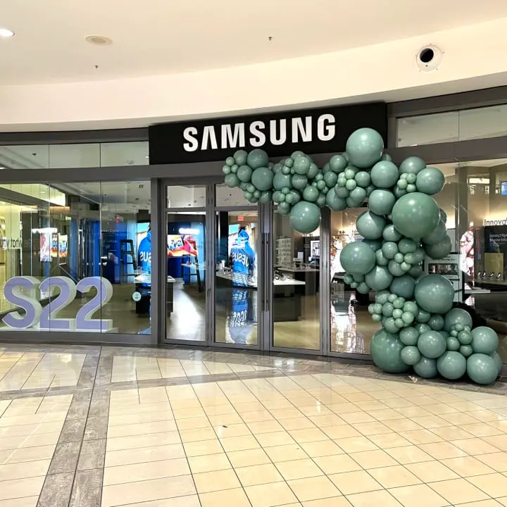 a samsung store is decorated with balloons and a large sign in the middle of the store's entrance