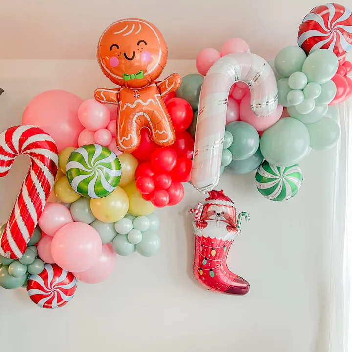 a bunch of balloons that are on a wall with a gingerbread man on top of one of the balloons