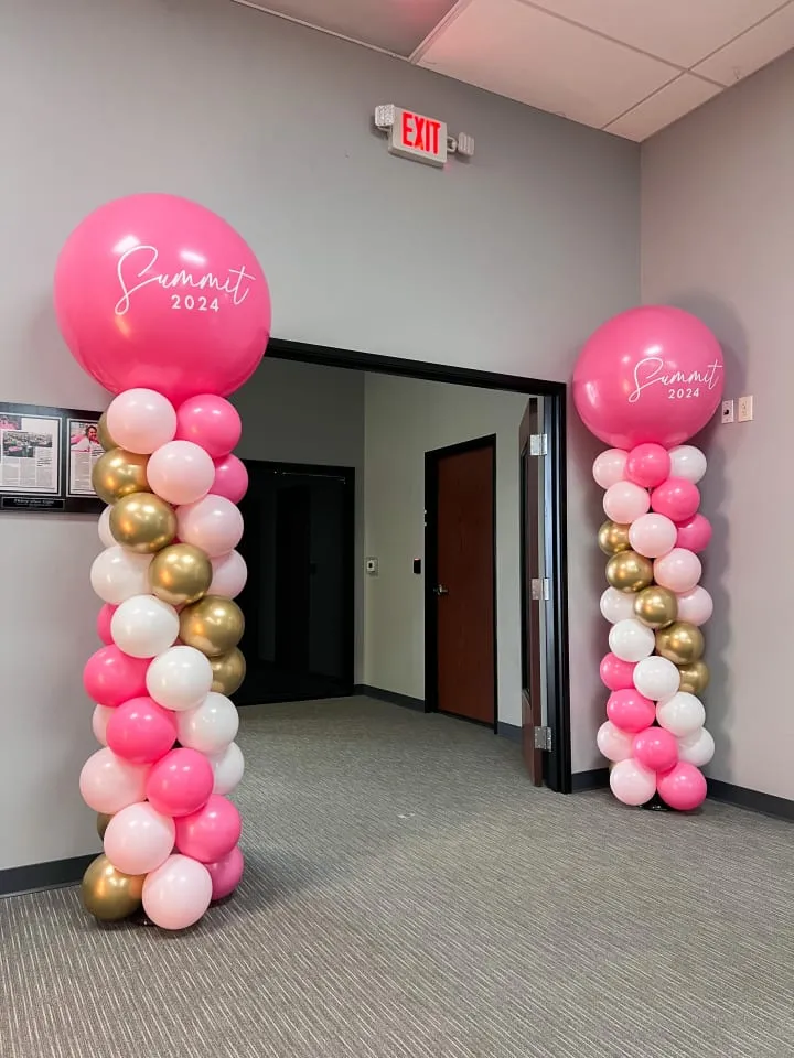 a hallway decorated with pink, white and gold balloons and a pink and gold balloon arch with a pink and gold balloon