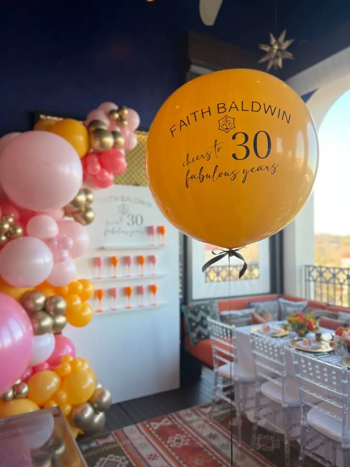 a balloon with the number 30 on it in front of a table with a bunch of balloons on it