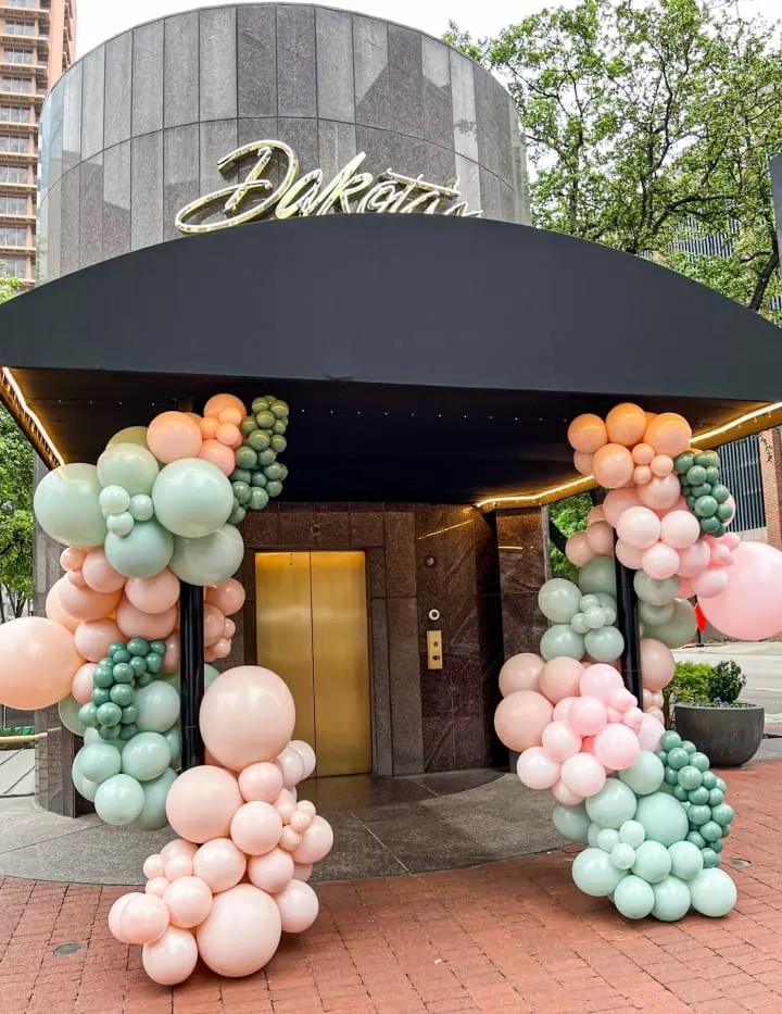 a bunch of balloons in front of a building with a black awning and a black awning over the entrance