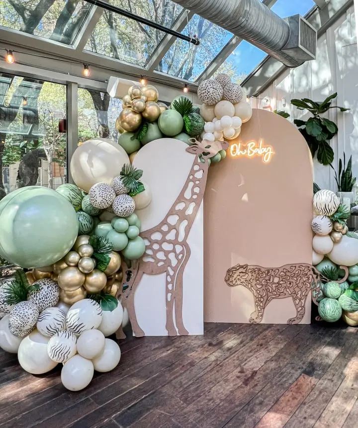 a display of balloons and a giraffe sign in a glass room with a wooden floor and a wooden floor